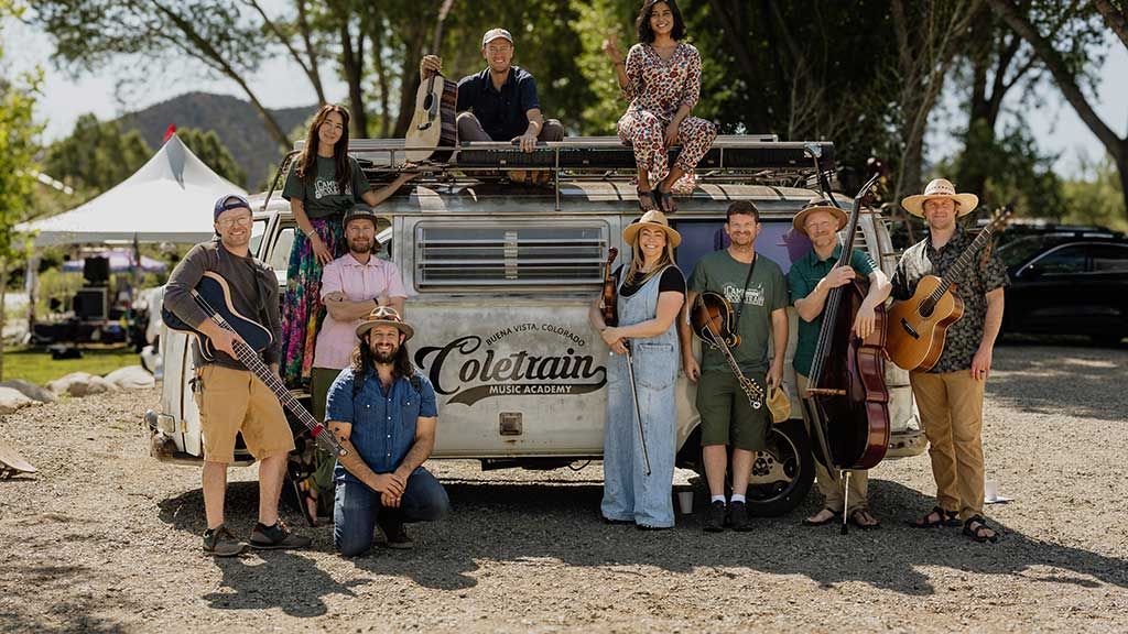 Musicians with instruments in front of vintage van.