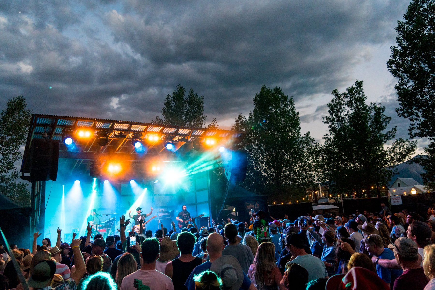 Outdoor concert with colorful stage lights and crowd.