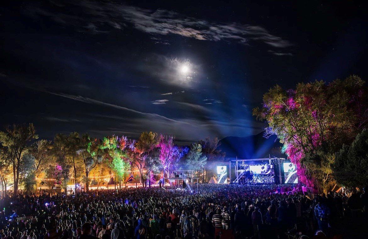 Night music festival with colorful lights and crowd.