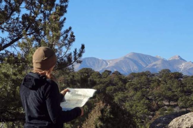 Woman reading map in front of mountains