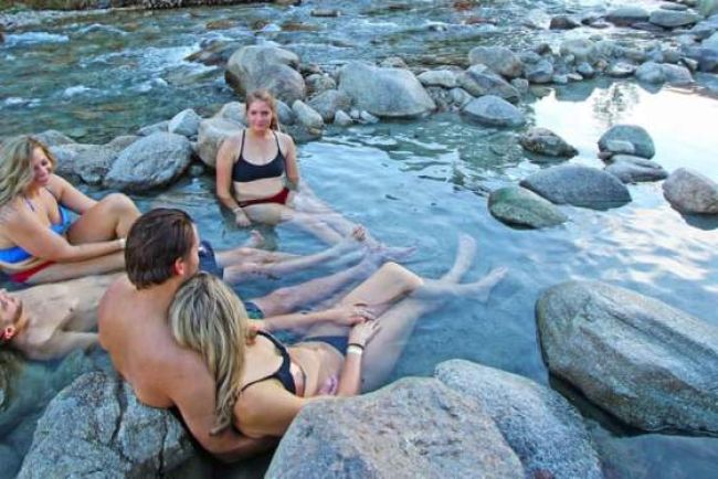 People relaxing in hot spring by the river.